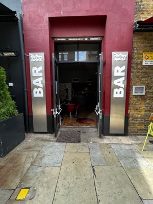 Bar entrance. Glass double doors with grey frame. Pull from middle to open. Small step at foot of door.