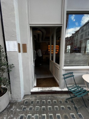 One step up through door. Glass door with beige frame. Push from right to open.