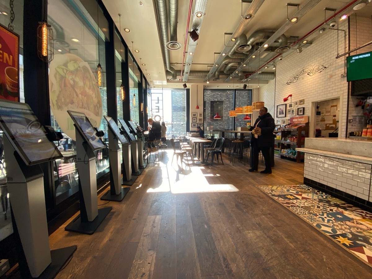 From entrance facing left. Ordering screens on left. Counter to right. Tables and chairs ahead.