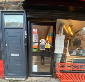 Glass door with black frame ahead. Push black handle on right to open.
