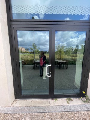 Black-framed glass pull door from right to open. Small step along door.