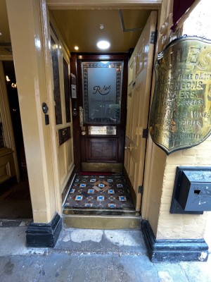 One step up through yellow wood door. Push from left to open. Second door ahead.