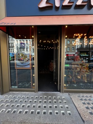 Glass door with brown frame. Push from left to open. Small bump at foot of door.