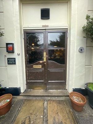 Double brown doors with glass panels. Push in center to open.