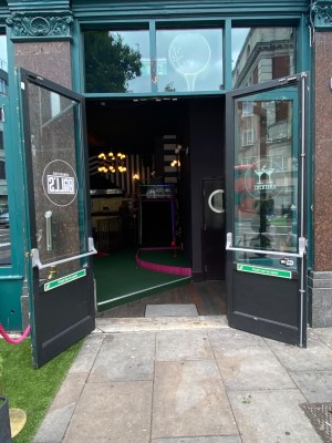Main entrance are aqua framed push doors pulled open. Small bump along doors.