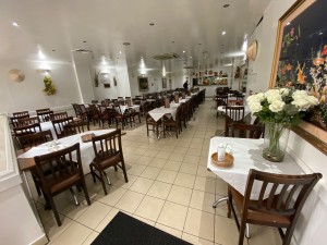 From entrance, looking straight ahead. Tables and chairs on left and right with middle path.