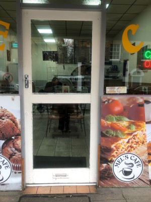 Glass door with white frame. Push handle on left to open.