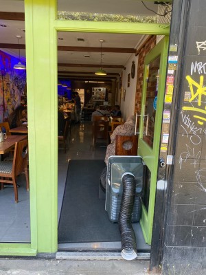 Green framed glass push door (handle on left). One step along door.