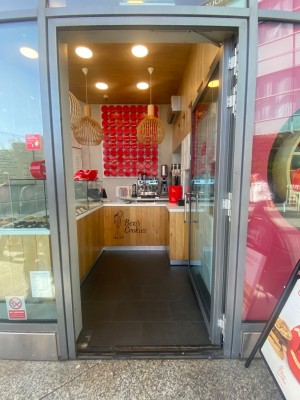 Glass door with grey metal frame. Push from left to open.