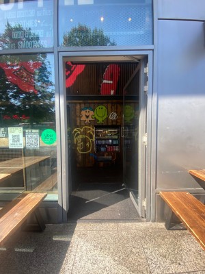 Glass door with grey metal frame. Push from left to open.