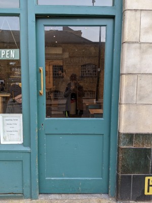 Glass and wood door with green frame and metal handle. Push to open.