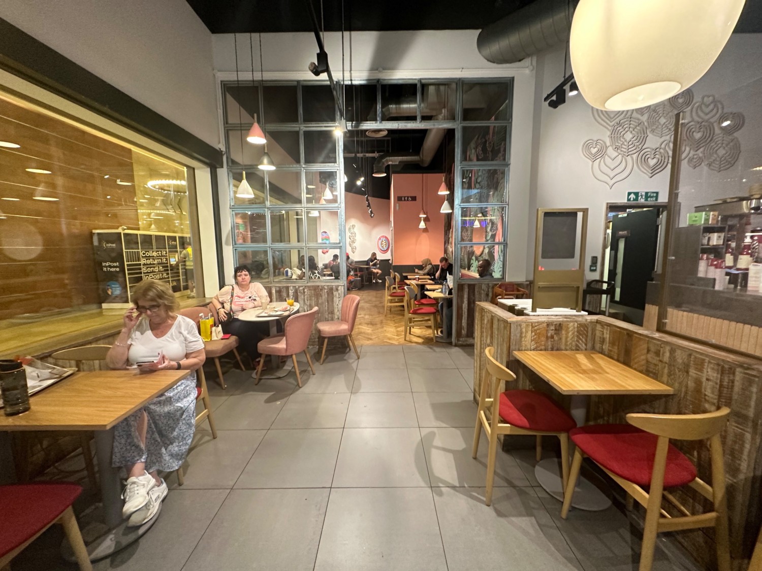 From middle of seating facing straight. Tables and chairs to left and right. Centre path leads to open archway to back area.