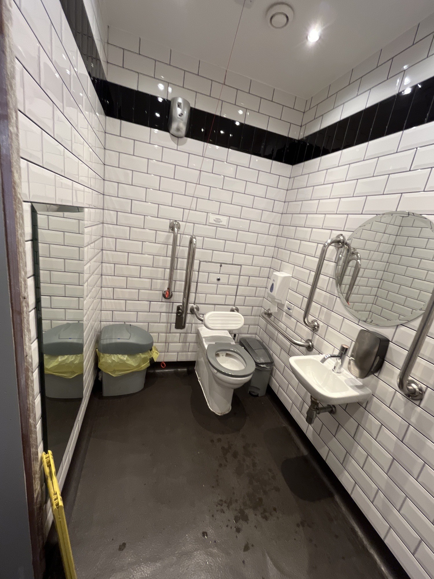 From bathroom door facing left. Sink on right wall. Toilet on back right. Emergency pull cord to left of toilet.