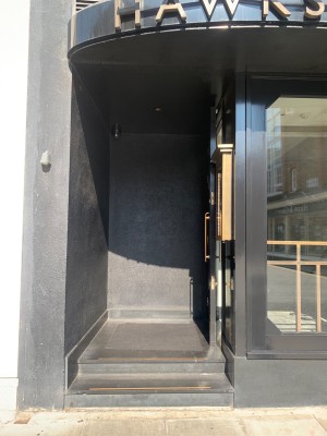 From street, door set into the building with two steps leading to platform, door on right.