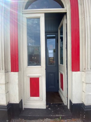First set of doors are glass with red and white frames. Push from middle to open.