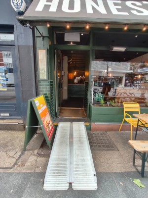 Facing entrance. Path ahead to ramp on request to door. Green framed door. Push handle on right to open.