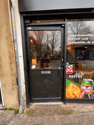 Glass door with black frame ahead. Push metal handle at right to open.