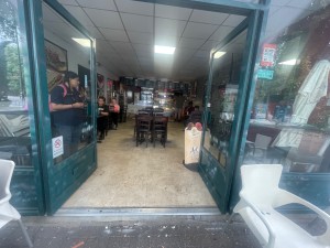 From the street looking Straight at main entrance. One step up. Wide glass doors. Push in the center to open.