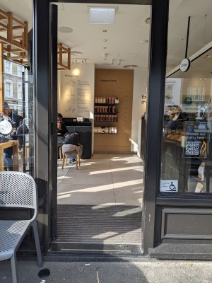 Glass door with black frame and metal handle on right. Push to open.