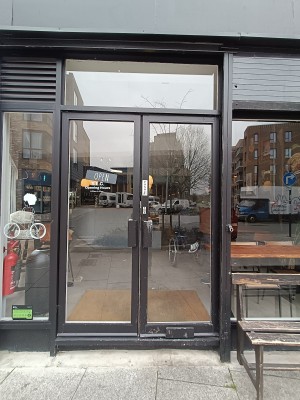 Glass doors with black, metal frame. Push black, metal handles in middle to open.