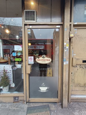 Glass door with yellow frame. Push yellow handle on left to open.