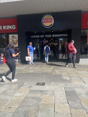 Entrance to Burger King, level access, automatic sliding doors (left open this day) busy street, queue to door