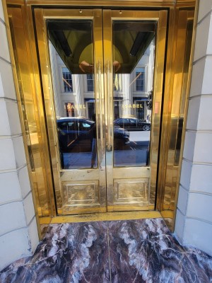 Double gold and glass doors. Pull to enter. Handles center.