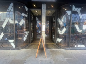 From the street looking straight at entrance. In the centre pillar. Enter left or right of pillar. Built in ramp with small bump.