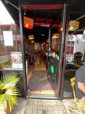 Glass door with black frame. Push from left to open.