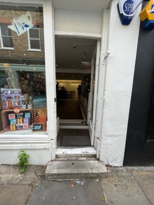 Glass door with white frame. Push door to open via handle on the left.