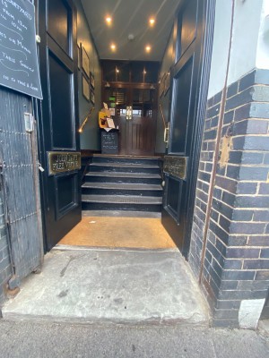 1 step leading to preceding double push door with handle in the middle. Followed by steps with handrail on both sides leading to main entrance door.