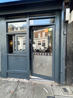 Glass door with blue wooden frame ahead. Push from left to open.