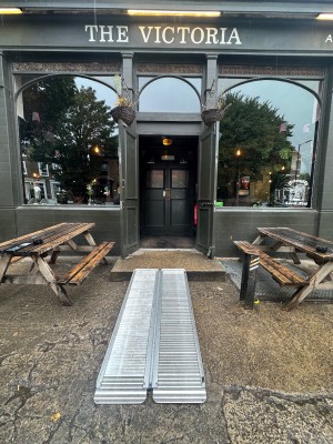 1 step with ramp upon request followed by double wood door. Pull.