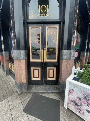 Black glass and wooden doors ahead. Push from centre to open.