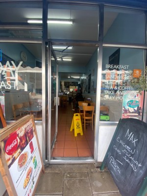 Grey framed glass door. Push grey handle on right to open. A-frame signs on both sides.