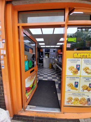 Glass door with orange metal frame. Push metal handle on right to open.