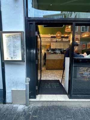 Glass door with black frame. Push from right to open. Step up at foot of door.