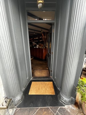 Glass door with grey frame. Push from left to open. Small bump at foot of door.
