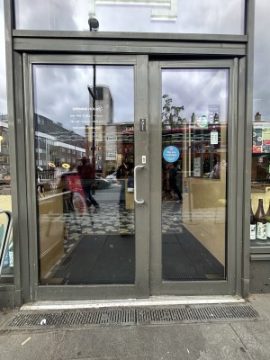 Glass door ahead with grey frame. Pull silver handle on right to open.