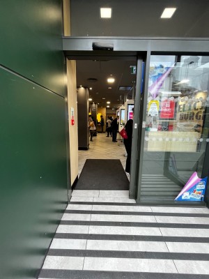 Glass door with dark green frame ahead. Door slides open to right. Built in ramp leads to door.