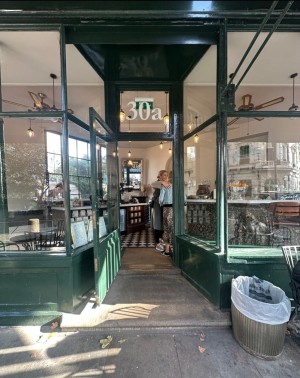 Green wood-framed glass door. Pull from brass handle on left to open. Two steps up before door.