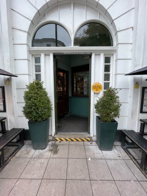 First set of doors ahead. One step before doors. Green wood-panelled glass doors. No handles. Push at centre to open.
