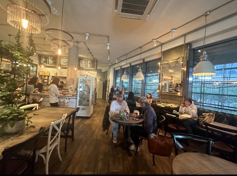 From seating path on main area with division on the left followed by tables. Tables on the right center. Half booth on the right. Path ahead to toilet