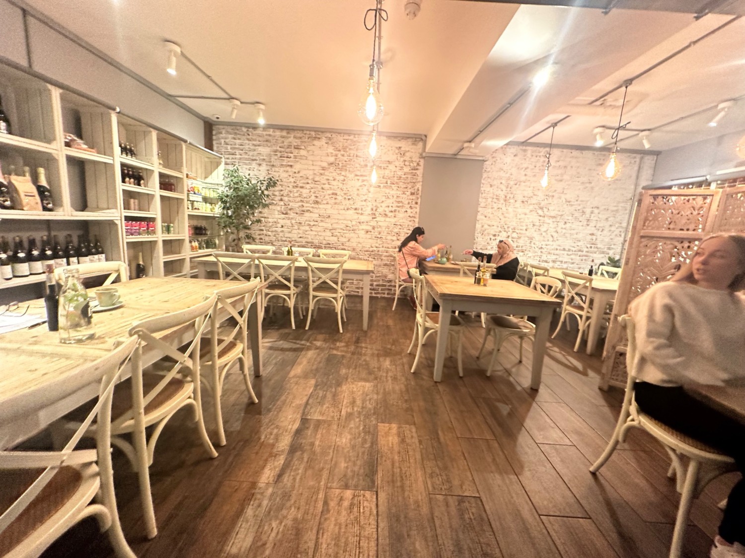 From top of steps facing ahead. Tables with chairs on left, right, and back walls, and in middle of space ahead.