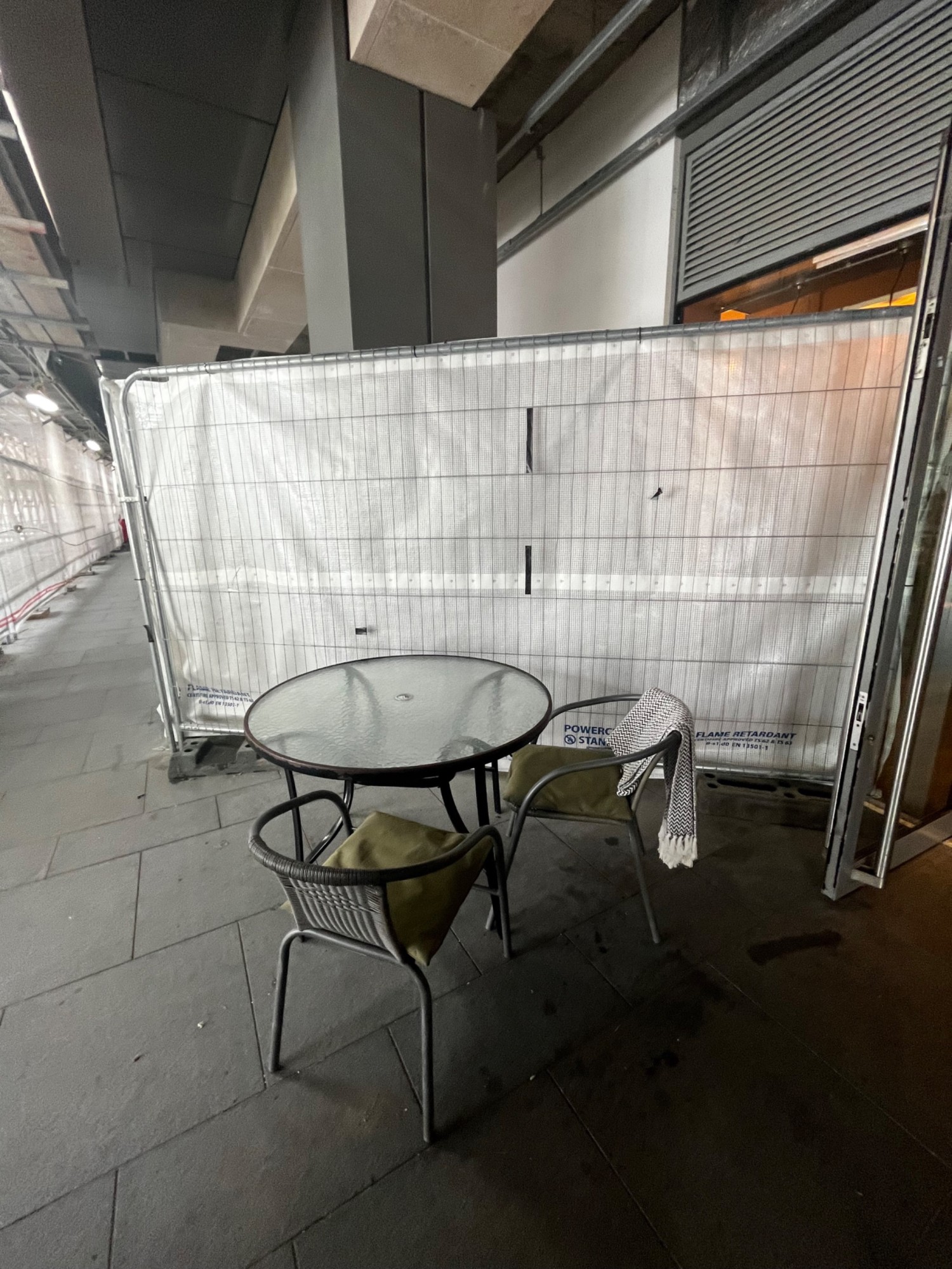 Table with chairs on outer wall on left of entrance when facing storefront.
