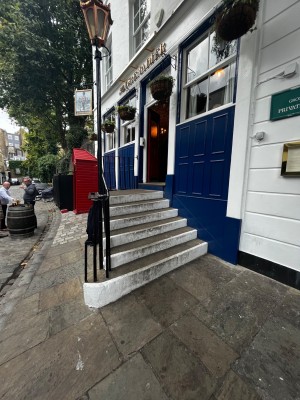 Staircase to door facing left from storefront. 6 steps to floor. Handrail on left. Door on wall of venue facing right at floor.