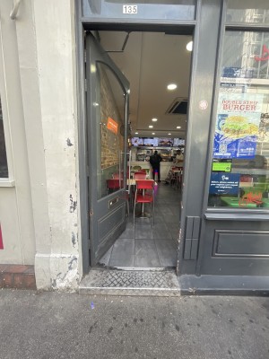 Glass door with grey frame. Push from right to open. One step up through door.