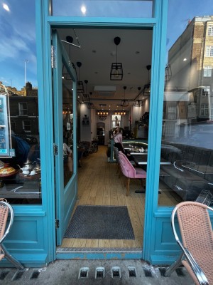 Glass door with blue frames. Push on right to open. One step up at threshold. Doormat after.