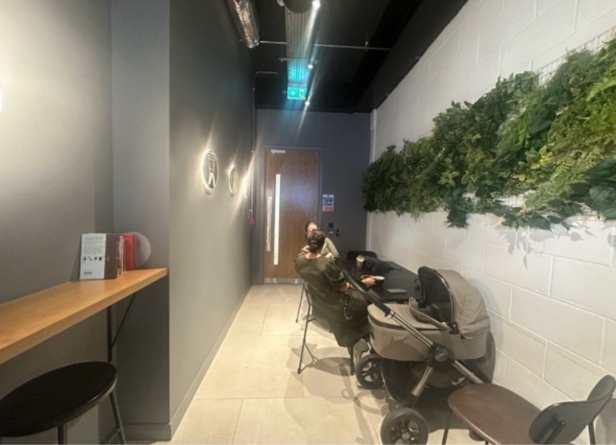 From end of high table facing straight. Half booth, tables and chairs continue along right. Path ahead to bathroom door on back.