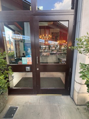 Glass doors with dark wooden frame ahead. Pull silver metal handle on left to open. Push silver button to open at left of door.